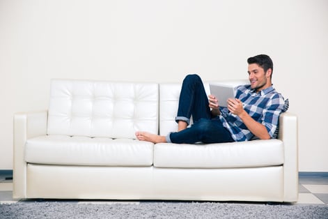 Portrait of a casual man lying on the sofa with tablet computer