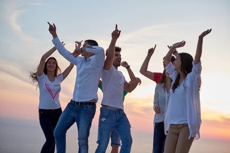 group of happy young people dancing and have fun on party in modern home bacony with sunset and ocean in background