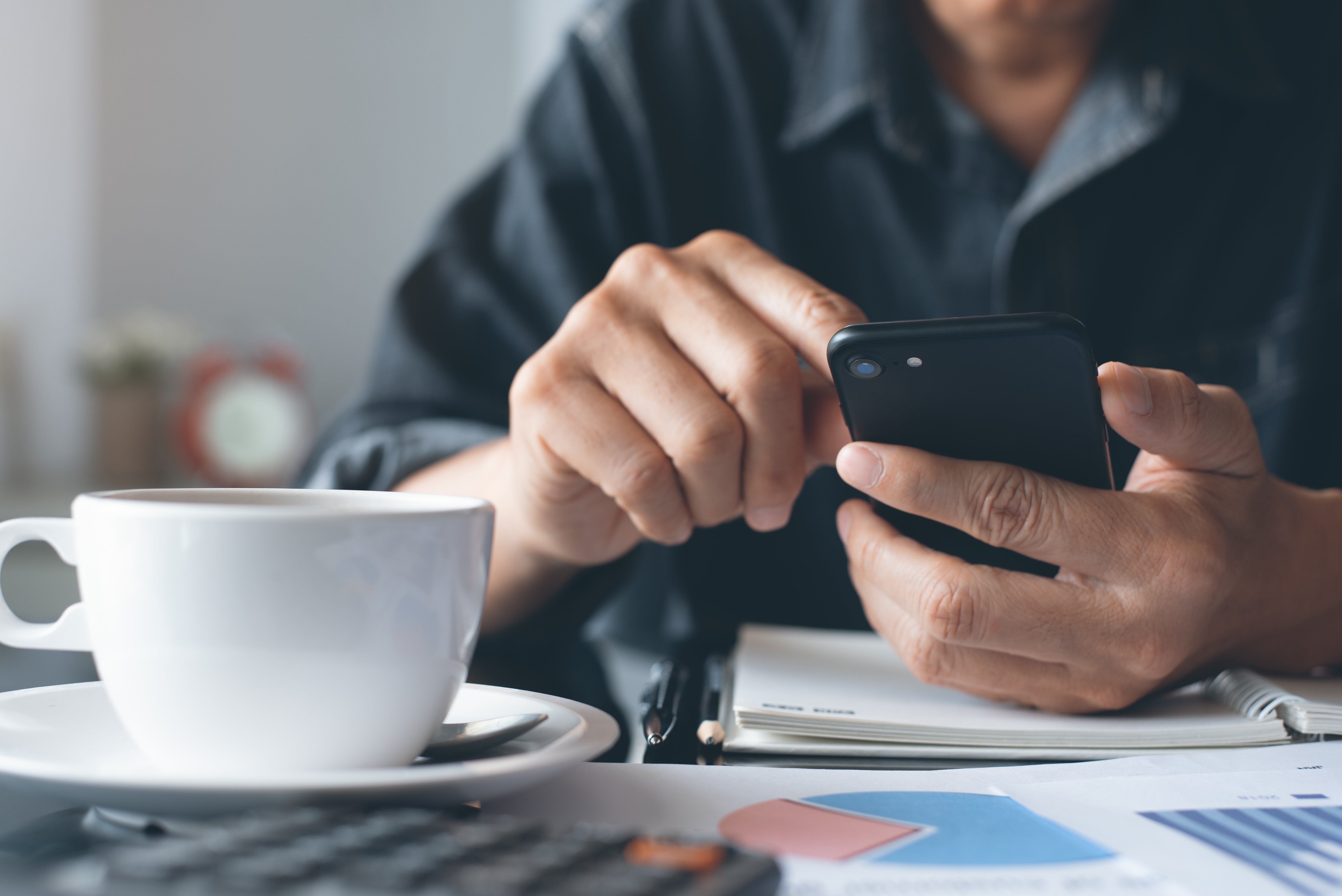 A close-up of a man's hand holding an iPhone. Looking for alternative options to a credit card, like using Beforepay's Pay On Demand™ can help to avoid paying high interest charges on credit cards.