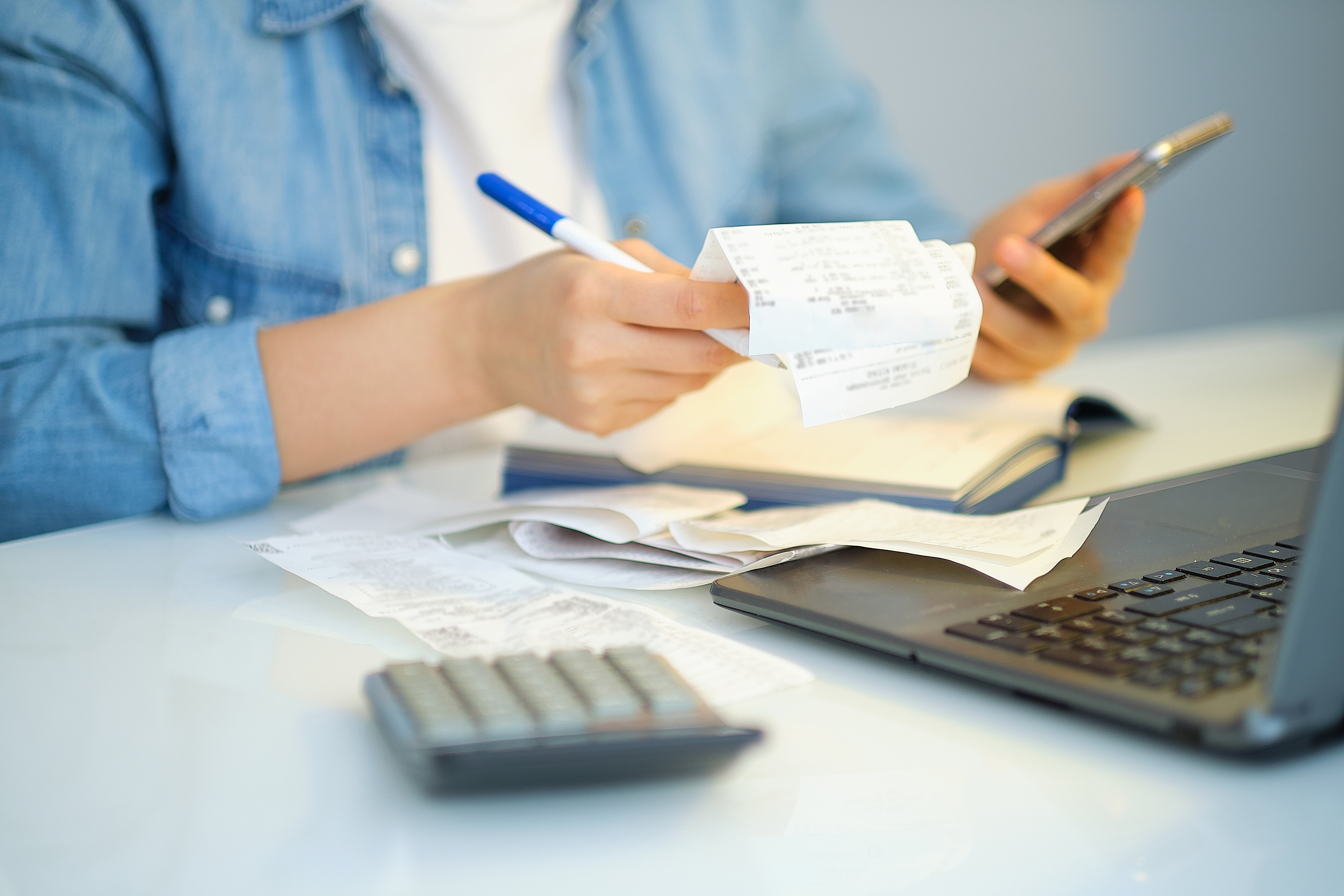 Person checking their receipts in front of their computer to maximise their tax return.