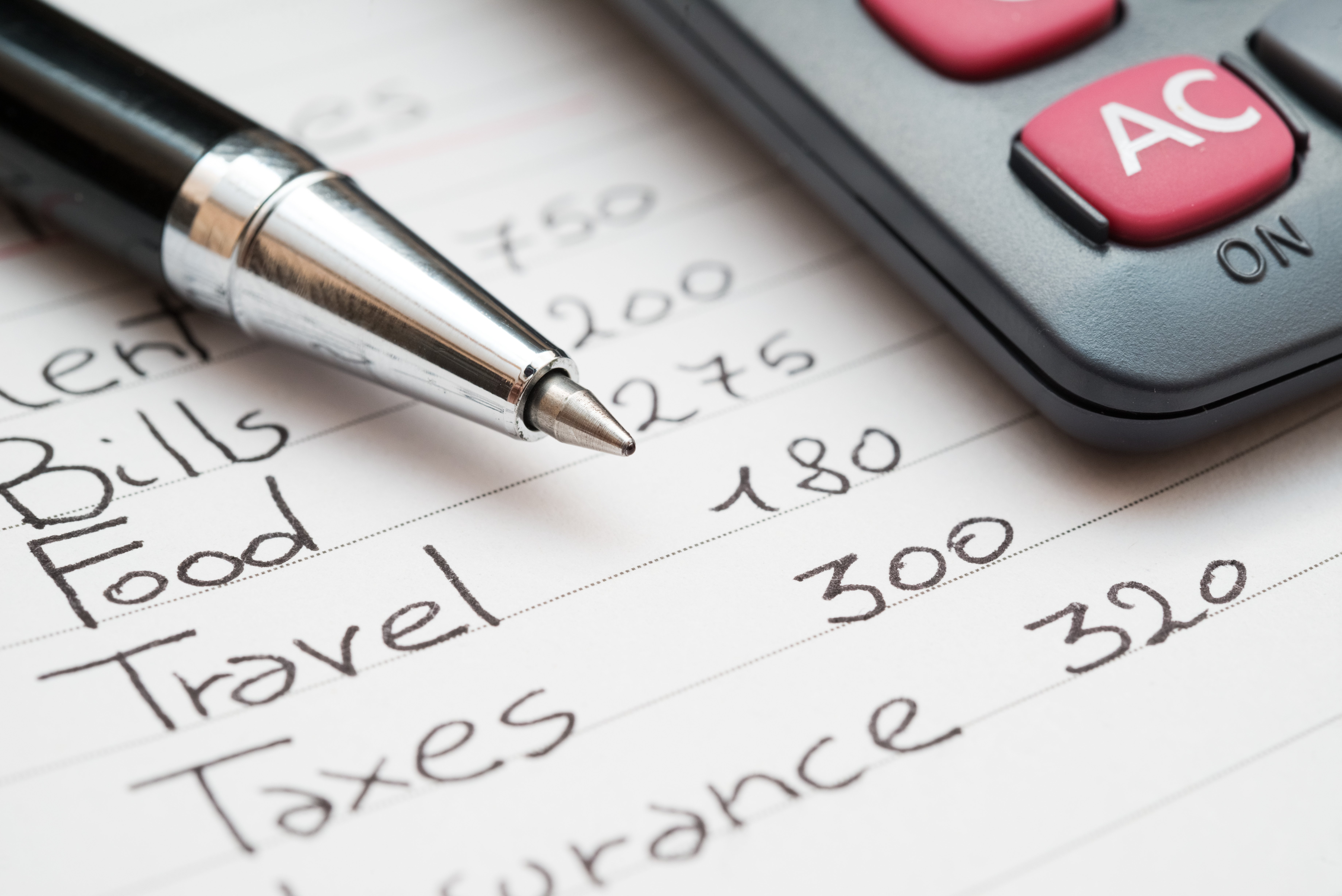 A pen and calculator sit on a notepad that contains a handwritten list of living expenses. Working Australians are feeling the impact of inflation and the rising cost of living.