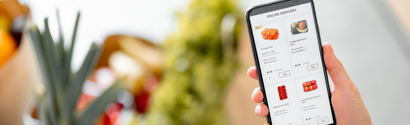 Hand holding a phone with an online grocery on the screen.