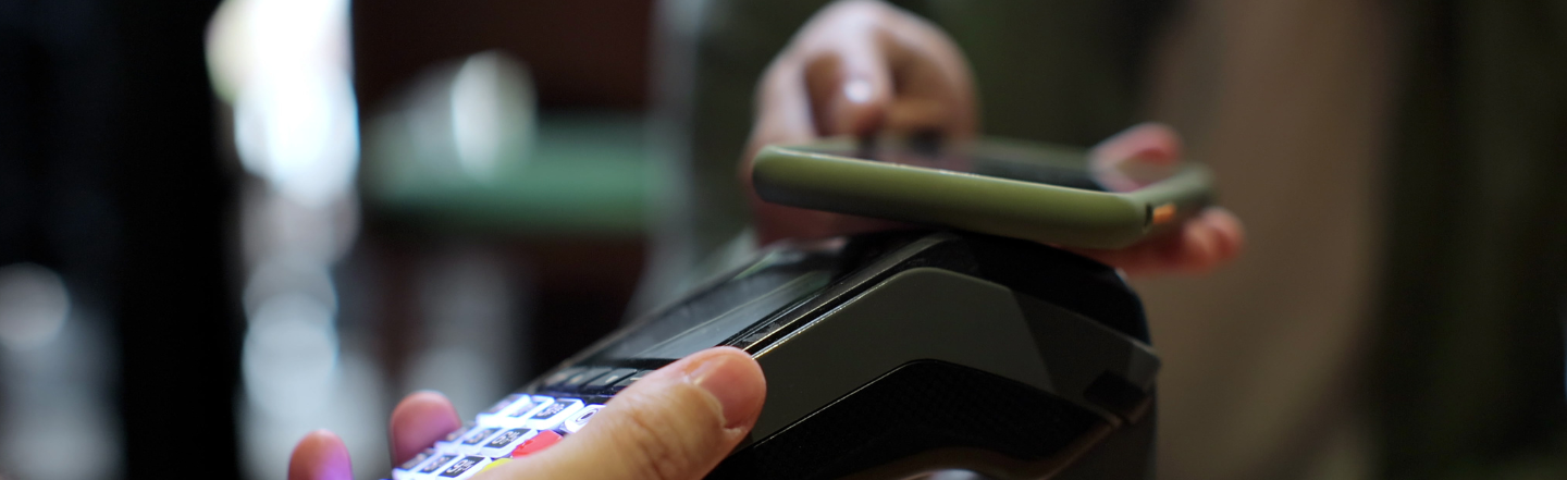 Close up of phone held near EFTPOS machine to process payment