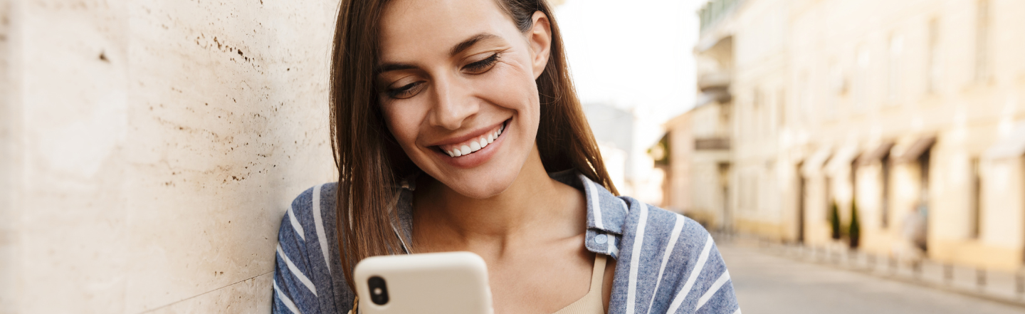 Woman smiling holding her phone to apply for a pay advance