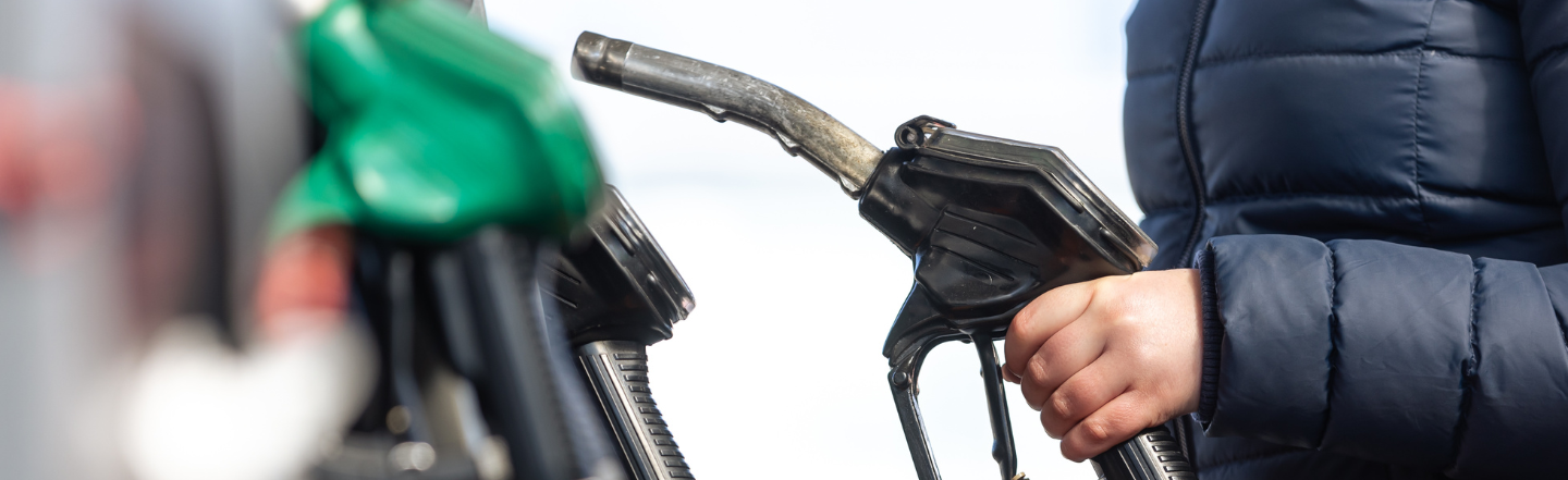 Person holding petrol pump at petrol station