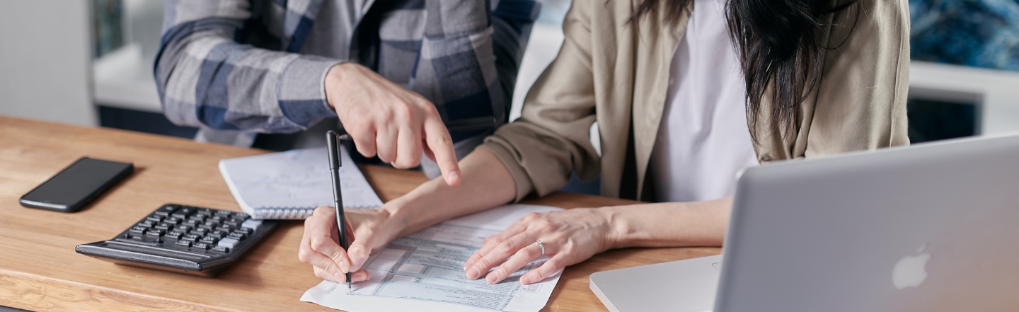 Two people examining expenses on a sheet of paper