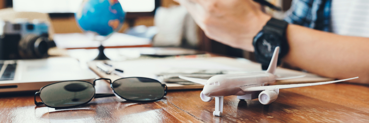 Black sunglasses and toy plane on wooden desk