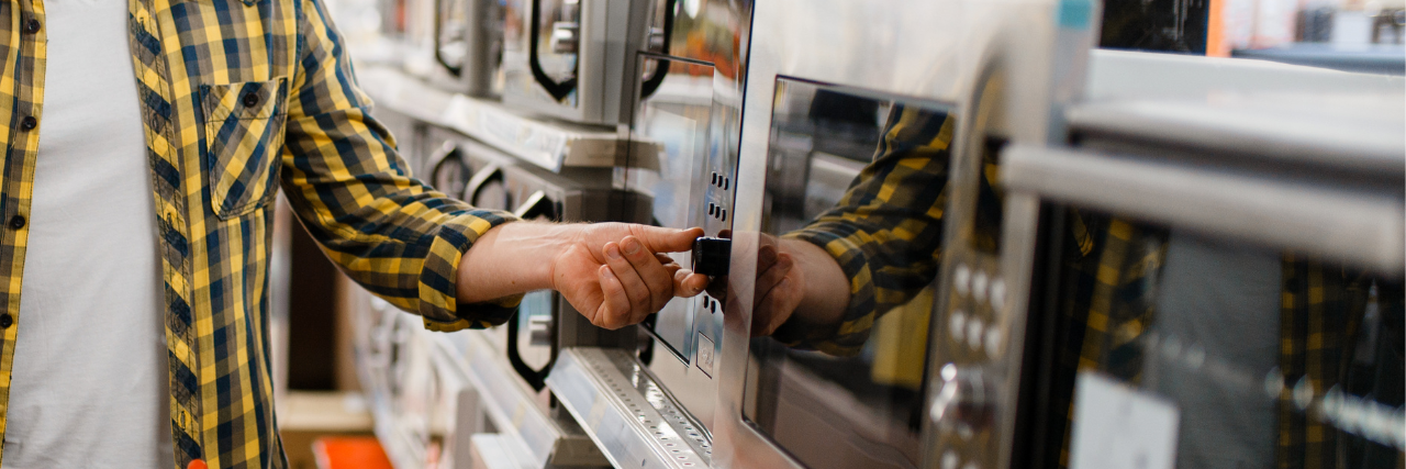 Person in home goods store turning knob on microwave