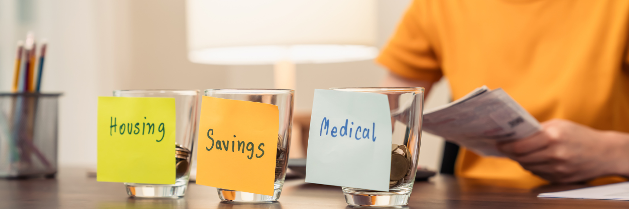 Lady budgeting with three glasses in front of her with labels housing savings and medical