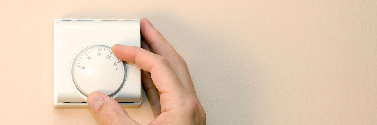 Close-up of hand adjusting thermostat