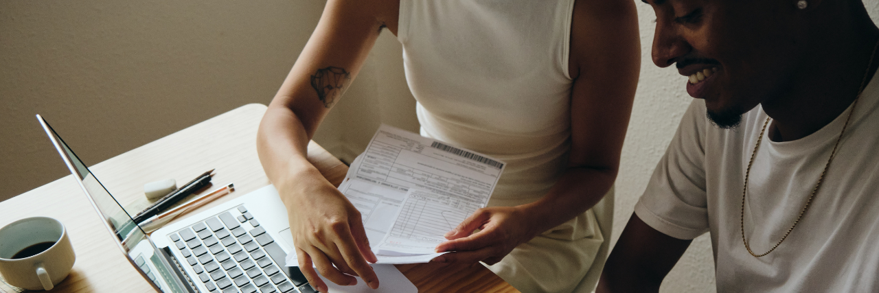 Couple sitting at laptop looking through financial documents
