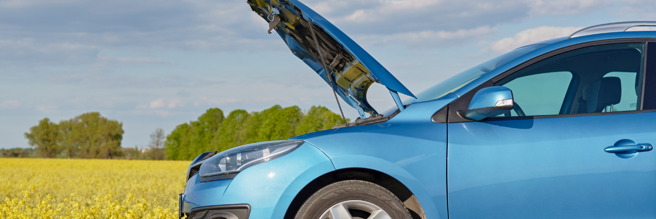 Blue car broken down with hood up on side of road