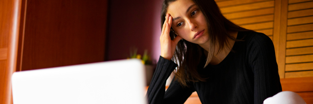 Girl sitting in front of laptop thinking