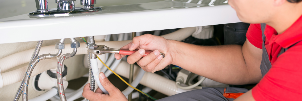 Plumber fixing pipes under a sink.