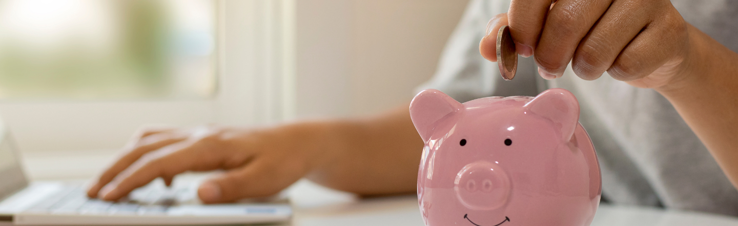 Person saving money using a piggy bank