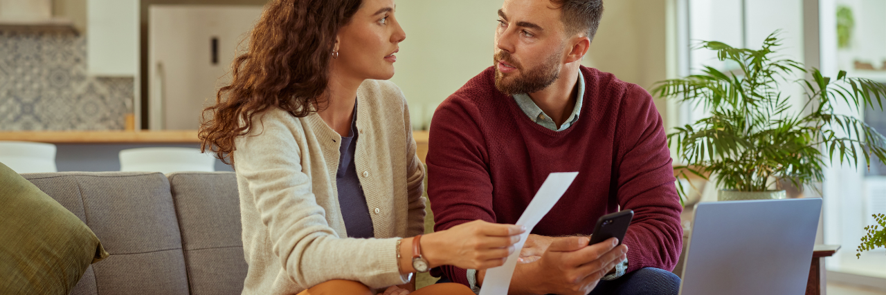 Couple reviewing bills and finances at home while discussing loan repayments and debt consolidation.