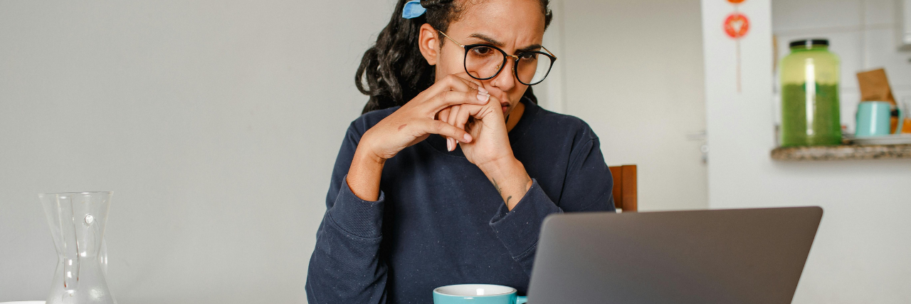 Woman concentrating on her laptop while reviewing personal finances and debt repayment options.